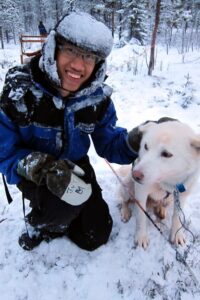 The author posing with a white sled dog in Kiruna