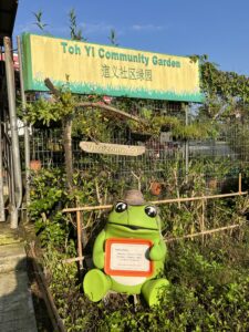 An adorable frog wearing a floppy straw hat welcomes you to Toh Yi Community Garden.